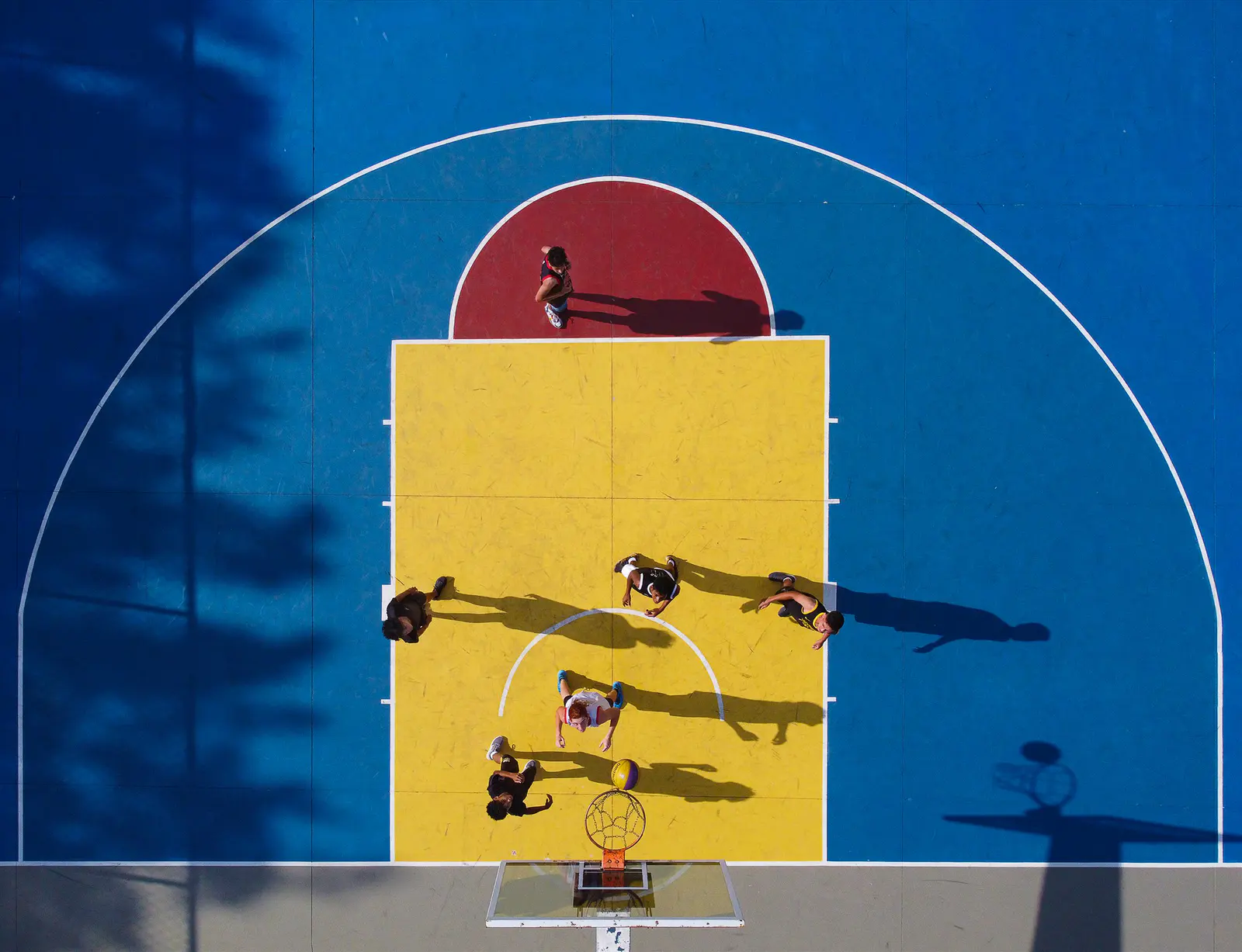Partida de basquete fotografada verticalmente sobre a quadra
